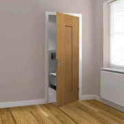 Wooden door in a room with light-colored walls and wooden floor.