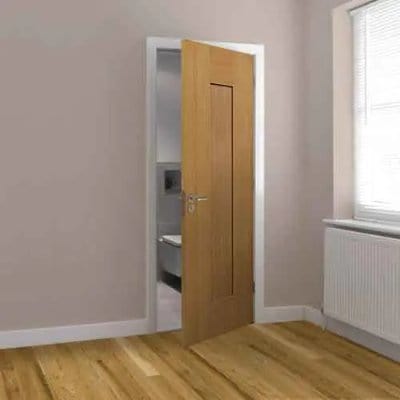 Wooden door in a room with light-colored walls and wooden floor.