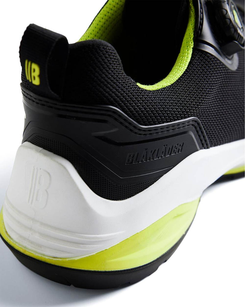 Black and white athletic shoe with green accents on a light gray background