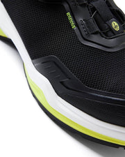 Close-up of a black athletic shoe with white sole and yellow accents on a white background