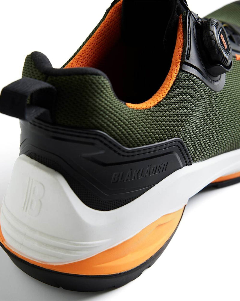 Green and orange safety shoe with brand name on a white background