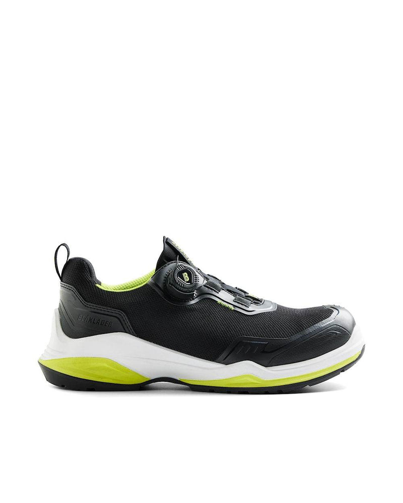 Black and white athletic shoe with green accents on a white background