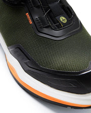 Close-up of a green athletic shoe with black and orange accents on a white background