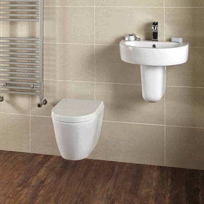 Bathroom setup with a wall-mounted toilet and a free-standing sink against tiled walls.