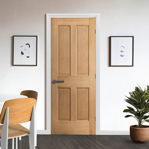 Wooden door with white frame in a room with chairs, plant, and wall art.