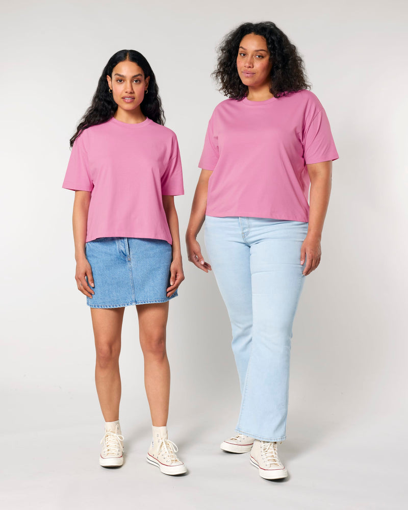 Two women wearing pink t-shirts and light blue jeans on a plain background