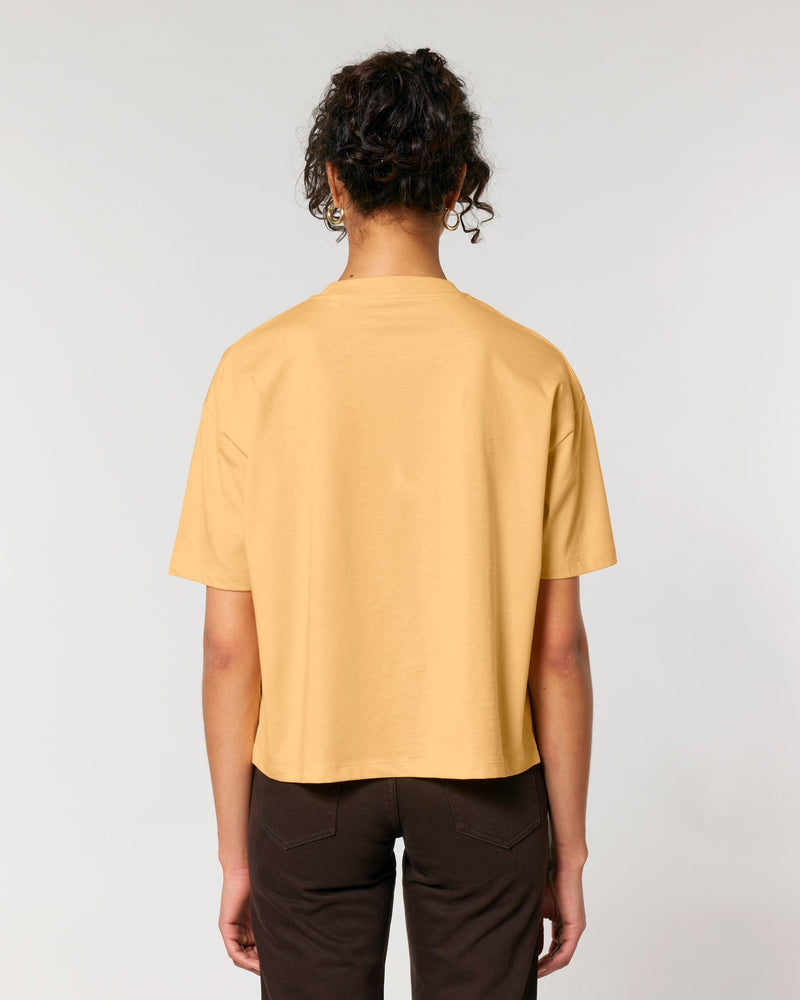 Person wearing a mustard yellow t-shirt and dark pants on a light gray background