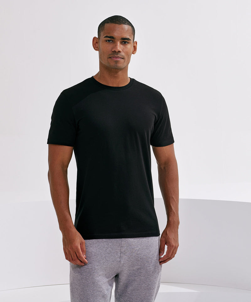 Man wearing a black t-shirt and gray pants against a white background