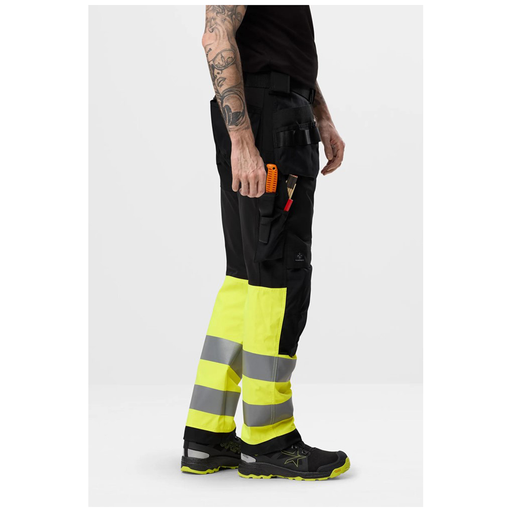 Person wearing high-visibility work pants with reflective stripes on a white background