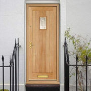 Wooden front door with glass panel on a white wall