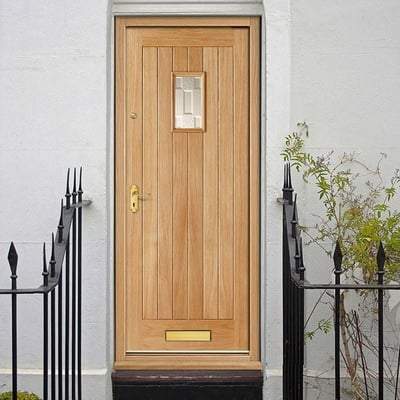 Wooden front door with glass panel on a white wall