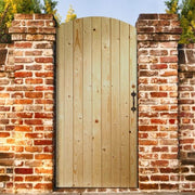 Wooden gate in front of a brick wall with trees in the background