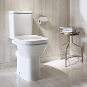 White toilet in a bathroom with tiled walls and a small stool.