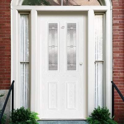 White front door with glass panels on a brick building